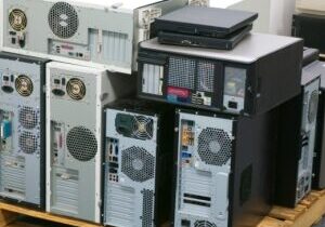 Pile of assorted desktop PC towers stacked on wooden pallet in warehouse